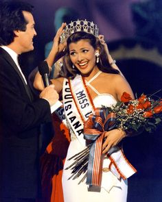 a man standing next to a woman wearing a tiara and holding flowers in her hand