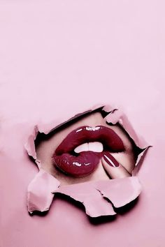 a woman's lips are seen through the hole in her pink wallpaper, which has been torn open