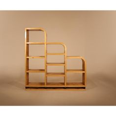 a wooden book shelf sitting on top of a white floor next to a brown wall