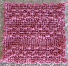 a pink crocheted square is shown on the floor with white carpet behind it