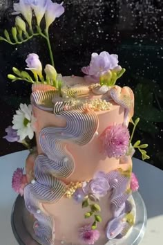 a pink and purple cake with flowers on top