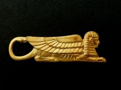 an ancient egyptian gold brooch depicting the sphinx