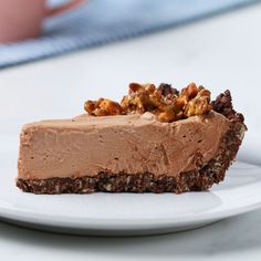 a piece of chocolate cheesecake on a white plate with walnuts and pecans