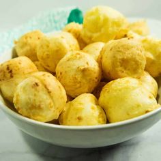 a white bowl filled with yellow food on top of a marble countertop next to a blue and white checkered napkin