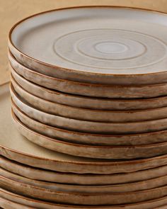 a stack of brown and white plates stacked on top of each other in front of a beige background