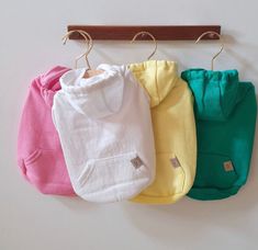 four different colored baby ones hanging on a coat rack