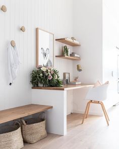 a white room with wooden shelves and baskets on the wall, along with a bench