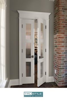 two white double doors in a room with brick wall and hardwood flooring on the side