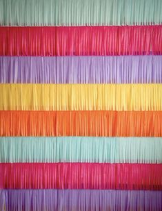 multicolored wall hanging on the side of a building with lots of fringes