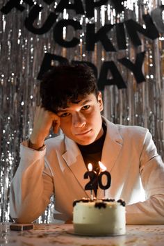 a man sitting at a table with a cake in front of him and the candles lit