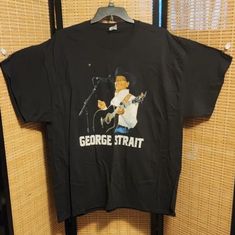 a black t - shirt with an image of george strait on it hanging from a rack