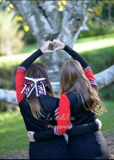 two girls in black and red shirts making a heart with their hands