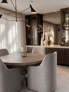 a dining room table surrounded by chairs and vases