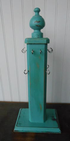 an old fashioned blue clock on top of a wooden table next to a white wall