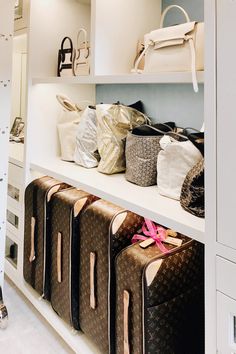 several bags are lined up on the shelves in a closet with white cabinets and drawers