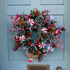 a christmas wreath with candy canes, pine cones and other decorations hanging on the front door