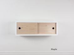 a white shelf with two black holes in it and the word maple written on it