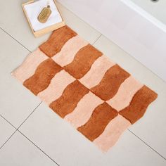 an orange and white rug sitting on top of a bathroom floor next to a bath tub