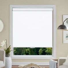 a living room filled with furniture and a large window covered in white blinds over the windowsill