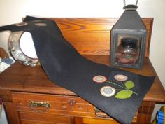 a table topped with a lamp and a black scarf on top of a wooden dresser