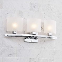 three light bathroom fixture with white marble wall tiles in the backgrounnd area