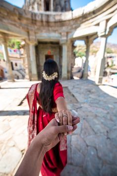 a woman in a red sari holding the hand of another person's hand