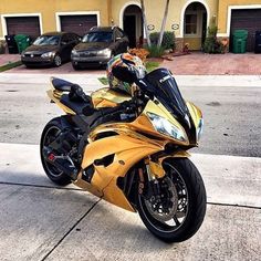 a yellow motorcycle is parked on the side of the road in front of a house