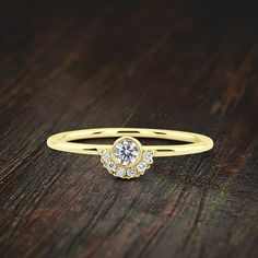 a yellow gold ring with three diamonds on it sitting on a wooden surface, close up