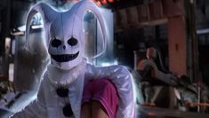 a person in a bunny costume standing next to a white rabbit with black spots on it's face