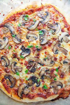 a pizza with mushrooms on it sitting next to a knife and fork