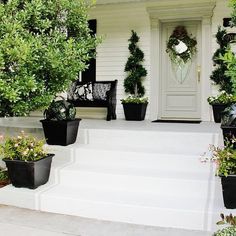 a white house with potted plants on the front steps