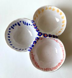 three small bowls with designs on them are sitting next to each other, one is empty