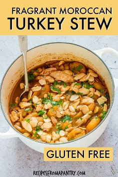 a pot filled with chicken and beans next to a spoon