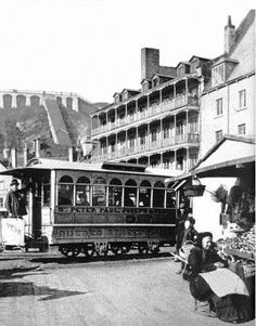 an old black and white photo of a trolley car in the middle of a town