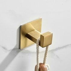 a bathroom hook with rope attached to it and a marble block on the wall next to it