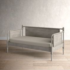 a white daybed sitting on top of a hard wood floor next to a wall