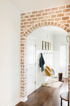 an archway leading into a living room with wood floors and white walls, along with a coat rack on the wall