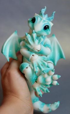 a hand holding a small blue and white dragon figurine