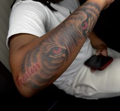 a man with a tiger tattoo on his arm holding a remote control in his hand