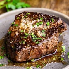 a piece of steak on a plate with parsley sprinkled around it's edges