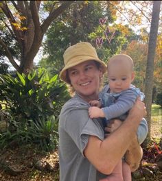 a man holding a baby in his arms and wearing a hat with hearts on it