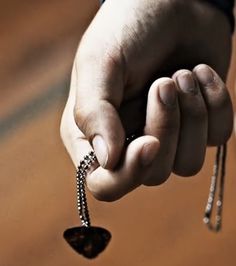 a person holding onto a chain with a small piece of metal on it's end