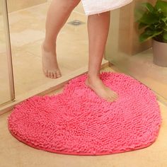 a person standing on a pink rug in front of a shower door with their feet sticking out