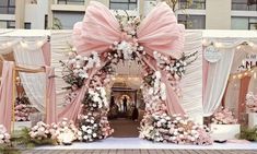 an outdoor wedding ceremony setup with pink and white flowers on the arch, decorated with lights