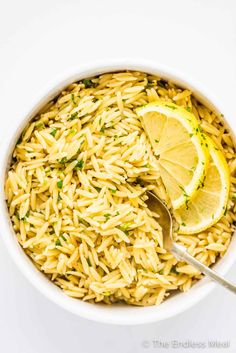 a white bowl filled with rice and lemon wedges