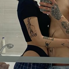 two people with tattoos are looking at their cell phones in the bathroom mirror while one person takes a selfie