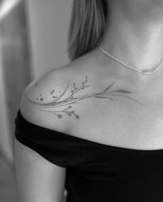 a woman wearing a black shirt has a flower tattoo on her left shoulder and chest