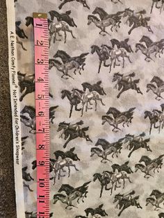 a ruler is next to a fabric with horses and jockeys on it, as well as a measuring tape