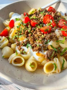 a bowl filled with pasta and meat on top of a table