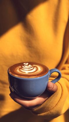 a person holding a cup of coffee in their hand with the cappuccino on top